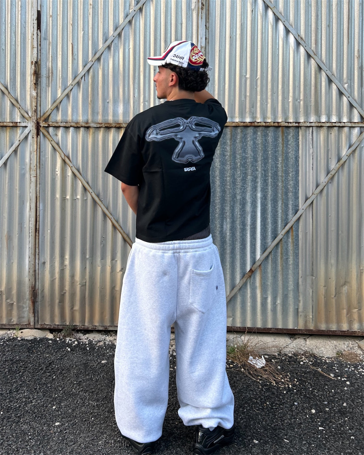Model wearing the 5Loop Chrome Arms black T-shirt, back view showing the graphic print